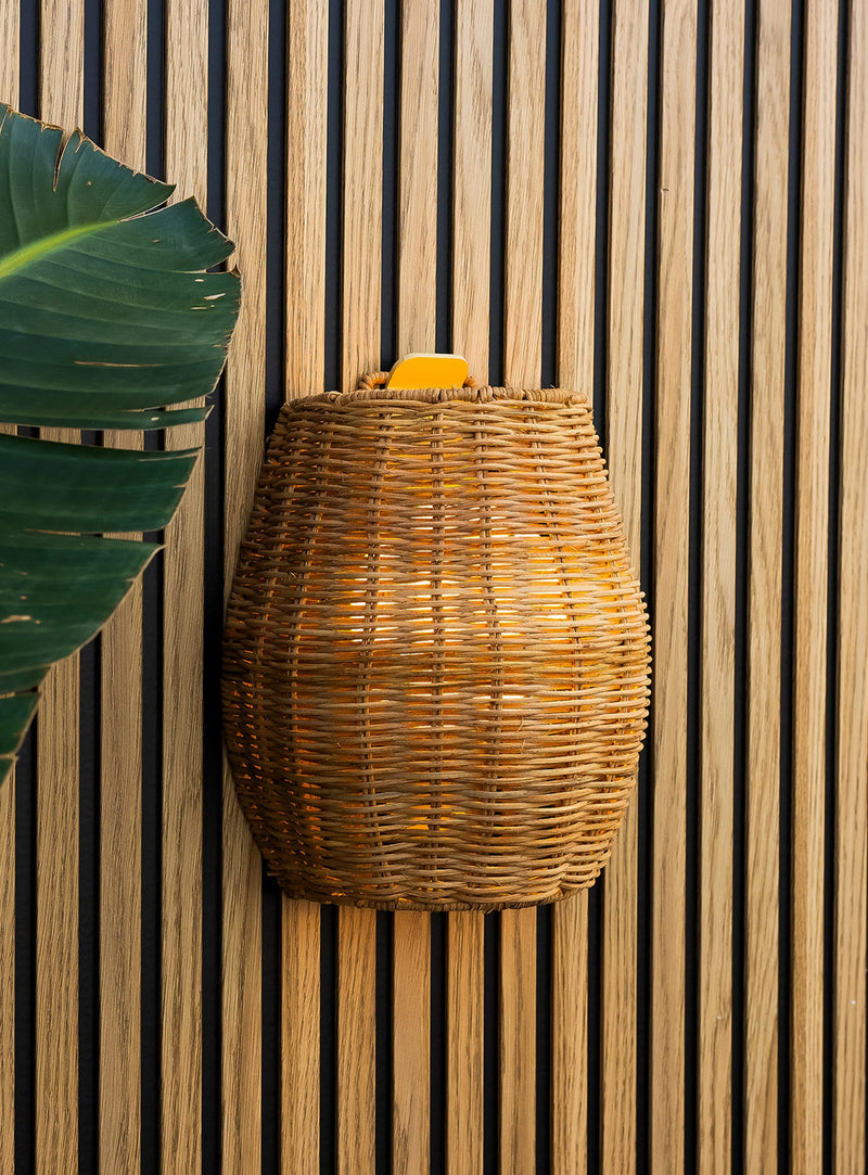 Saona 25 cordless wall lamp with handcrafted natural fiber shade and warm LED light for outdoor walls.