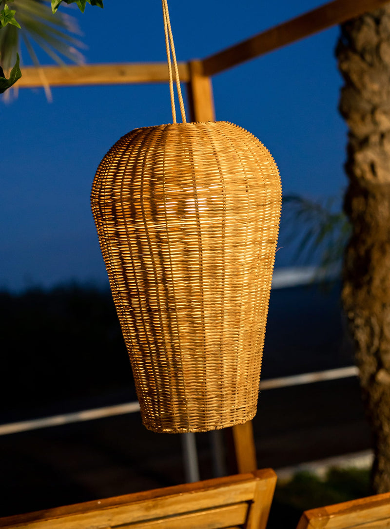 Saona 50 cordless pendant lamp with natural fiber shade hanging above outdoor dining area.