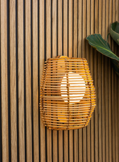 Bossa 25 cordless wall lamp with natural fiber shade and warm LED light, perfect for outdoor ambiance.