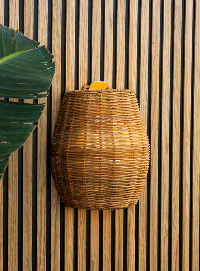 Saona 25 cordless wall lamp with handcrafted natural fiber shade and warm LED light for outdoor walls.