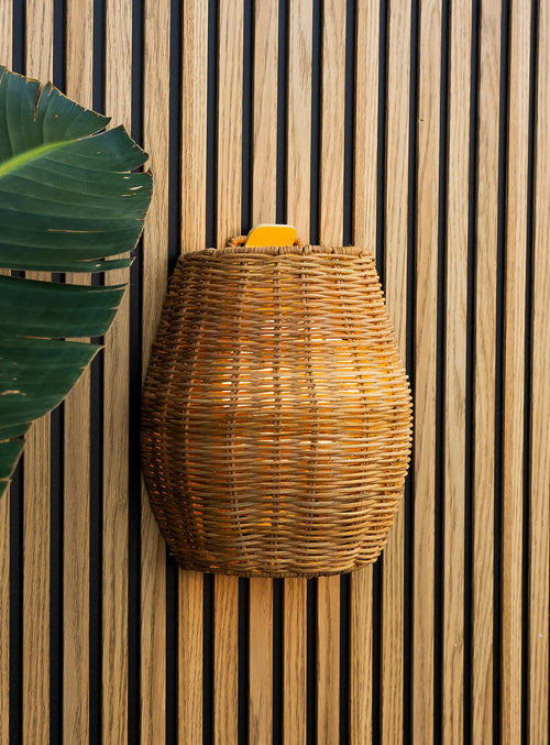 Saona 25 cordless wall lamp with handcrafted natural fiber shade and warm LED light for outdoor walls.